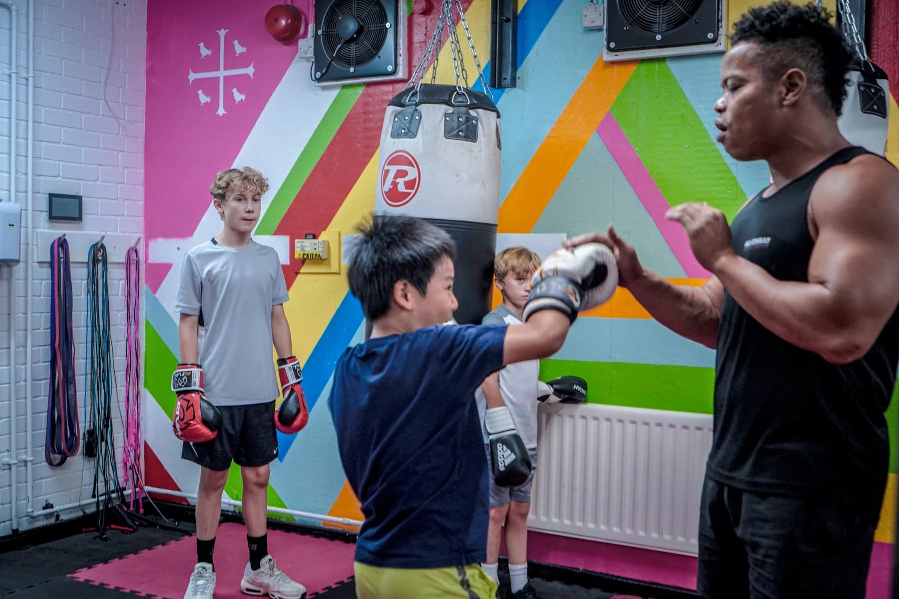A young participant practising punches with a coach during a martial arts session